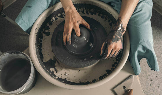 Craftsperson making pot in potter's wheel at workshop - ADF00047