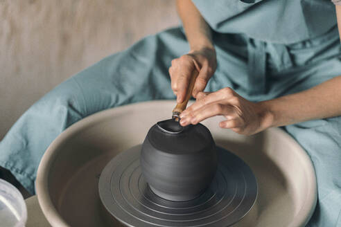 Potter shaping ceramic pot at workshop - ADF00048