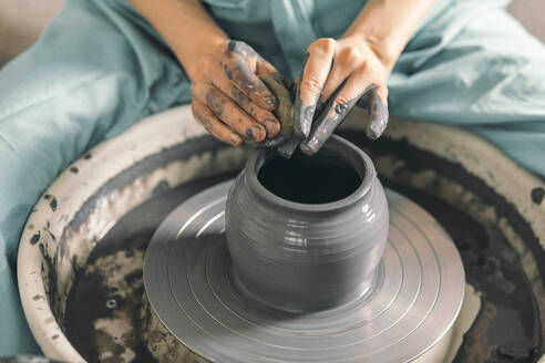 Messy hands of potter shaping pot at workshop - ADF00054