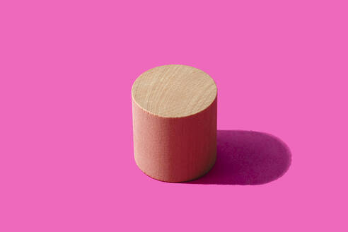 3D render of wooden cylinder against pink background - FLMF00953
