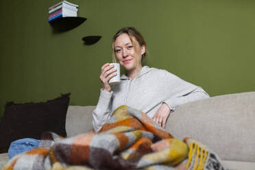 Young woman with mug relaxing on couch - MIKF00355