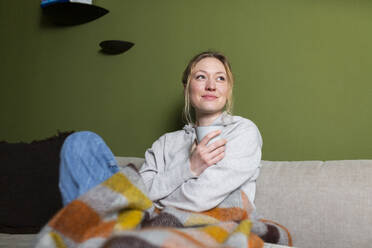 Thoughtful woman with mug relaxing on couch - MIKF00357