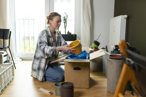 Junge Frau beim Auspacken von Containern aus einem Karton zu Hause - MIKF00362