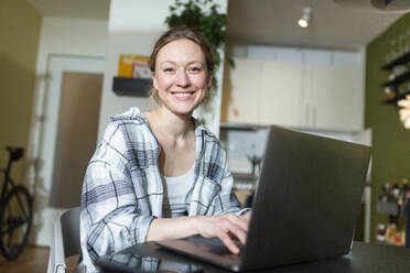 Smiling freelancer working with laptop at home - MIKF00370