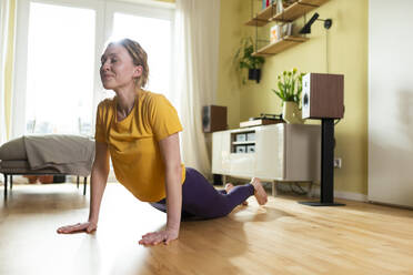 Junge Frau übt Yoga zu Hause - MIKF00381