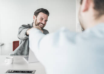 Glücklicher Geschäftsmann gibt seinem Kollegen im Büro einen Faustschlag - UUF28557