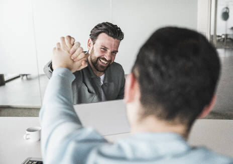 Glücklicher Geschäftsmann, der einem Kollegen im Büro die Hand drückt - UUF28558