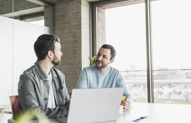 Businessmen discussing with each other at office - UUF28563