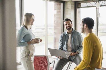 Businessman holding laptop planning with colleagues at office - UUF28585