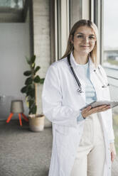 Smiling female doctor holding tablet PC at hospital - UUF28600