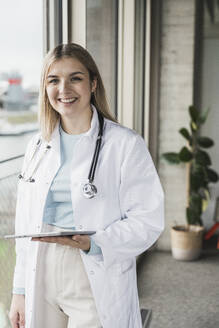 Happy female doctor wearing lab coat at hospital - UUF28601