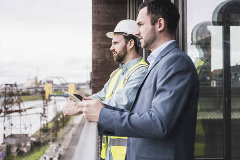 Architekt und Bauunternehmer stehen am Geländer - UUF28611