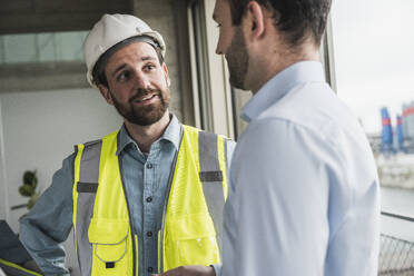 Building contractor discussing with architect at site - UUF28615