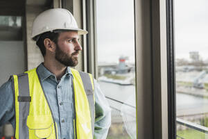 Bauunternehmer schaut auf der Baustelle aus dem Fenster - UUF28619