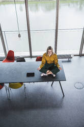 Geschäftsfrau meditiert auf dem Tisch im Büro - UUF28658
