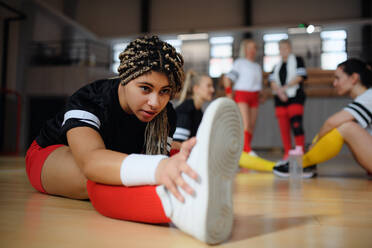 Eine Gruppe von Mehrgenerationen-Frauen, Spielerinnen einer Sportmannschaft, dehnt sich in der Turnhalle und wärmt sich vor dem Spiel auf. - HPIF09588