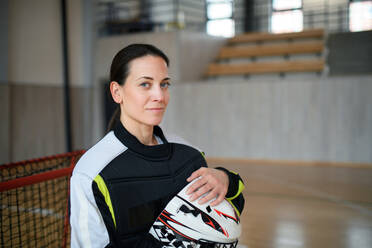 Nahaufnahme einer Unihockeytorhüterin mit Helm, die sich auf ein Spiel in einer Turnhalle konzentriert. - HPIF09601