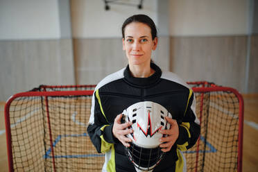 Nahaufnahme einer Unihockeytorhüterin mit Helm, die sich auf ein Spiel in einer Turnhalle konzentriert. - HPIF09602