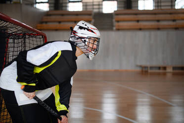 Nahaufnahme einer Unihockeytorhüterin mit Helm, die sich auf ein Spiel in einer Turnhalle konzentriert. - HPIF09603