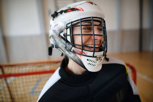 Nahaufnahme einer Unihockeytorhüterin mit Helm, die sich auf ein Spiel in einer Turnhalle konzentriert. - HPIF09605