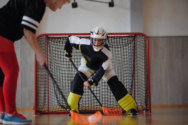 Nahaufnahme einer Unihockeytorhüterin mit Helm, die sich auf ein Spiel in einer Turnhalle konzentriert. - HPIF09610