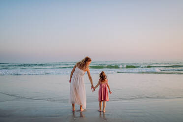 Mutter mit ihrer kleinen Tochter genießt die Zeit am Meer, Rückansicht. - HPIF09620