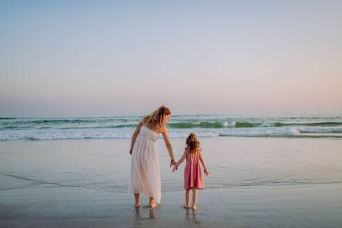 Mother with her little daughter enjoying time at the sea,rear view. - HPIF09620