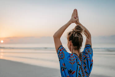 Rear view of young woman taking exercises at the beach, morning routine and healthy lifestyle concept. - HPIF09664