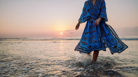 Low section of woman in orient dress enjoying ocean. - HPIF09665