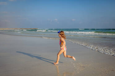 Little girl in swimsuit running out of sea, enjoying summer holiday. - HPIF09686