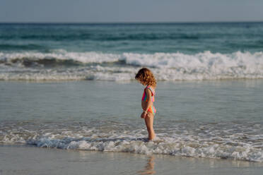 Kleines Mädchen im Badeanzug steht im Meer und genießt den Sommerurlaub. - HPIF09687