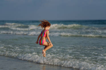 Little girl in swimsuit jumping in the sea, enjoying summer holiday. - HPIF09694