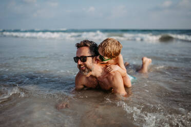 Vater mit seinem kleinen Sohn im Meer, der den Sommerurlaub genießt. - HPIF09703