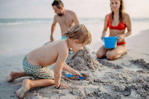 Glückliche Familie mit kleinen Kindern, die die Zeit am Meer in einem exotischen Land genießen und eine Sandburg bauen. - HPIF09713