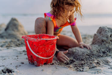 Kleines Mädchen spielt am Strand und baut eine Sandburg. - HPIF09716