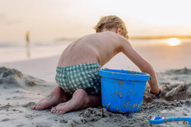 Kleiner Junge spielt am Strand und baut eine Sandburg. - HPIF09717