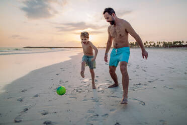 Vater mit seinem Sohn beim Fußballspielen am Strand. - HPIF09719