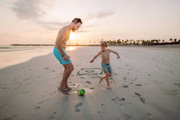 Vater mit seinem Sohn beim Fußballspielen am Strand. - HPIF09721