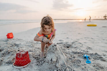 Little girl playing on the beach, building a sand castle. - HPIF09722