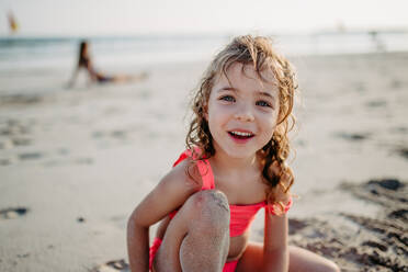 Little girl playing on the beach, digging hole in the sand. - HPIF09754