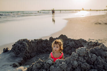 Little girl playing on the beach, digging hole in the sand. - HPIF09756