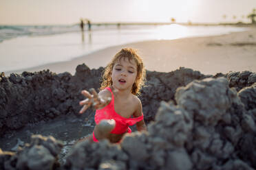 Kleines Mädchen spielt am Strand und gräbt ein Loch in den Sand. - HPIF09757