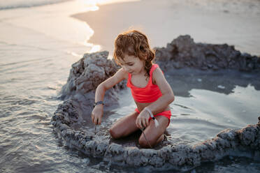 Kleines Mädchen spielt am Strand und gräbt ein Loch in den Sand. - HPIF09758