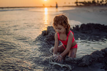 Kleines Mädchen spielt am Strand und gräbt ein Loch in den Sand. - HPIF09760