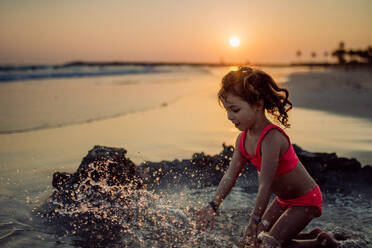 Little girl playing on the beach, digging hole in the sand. - HPIF09762