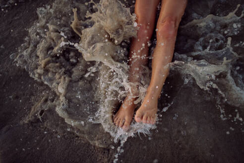 Draufsicht auf die Beine eines Kindes im Meer. - HPIF09765