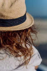 Rear view of little girl in straw hat looking at the ocean. - HPIF09777