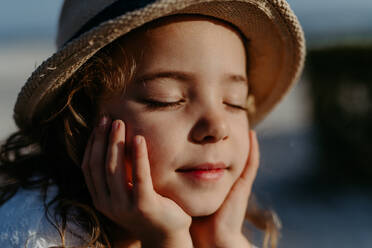 Portrait of little girl with closed eyes, at ocean. - HPIF09780