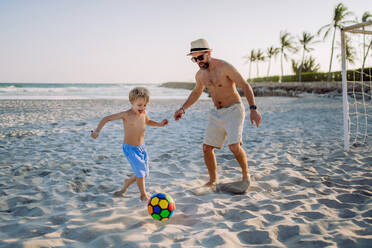 Father with his son plaing football on a beach. - HPIF09796