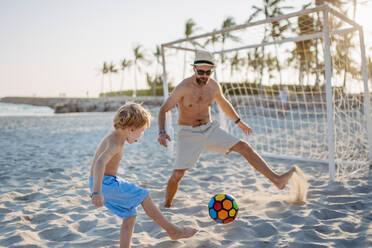 Vater mit seinem Sohn beim Fußballspielen am Strand. - HPIF09797